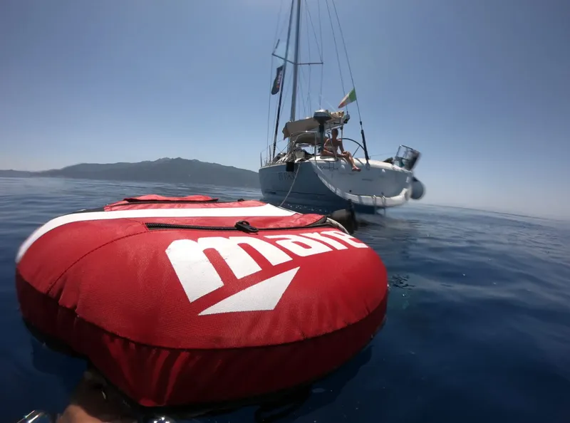Voilier amarré en mer avec une bouée rouge au premier plan