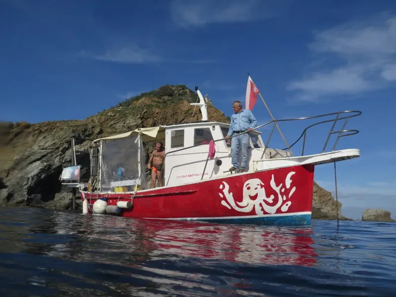 Bateau de plongée rouge et blanc avec un homme à bord en mer