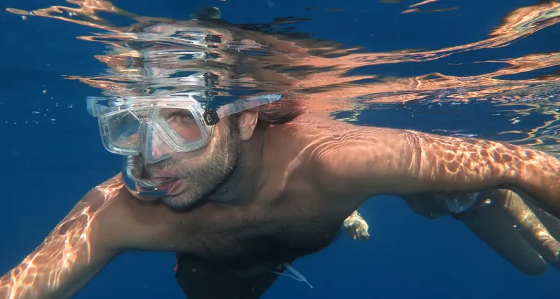 Plongeur avec masque nageant sous l'eau dans un environnement bleu