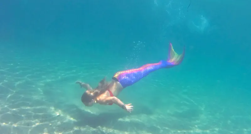 Une nageuse avec une queue de sirène colorée évolue sous l'eau