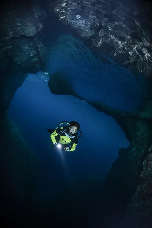 Plongeur explorant une grotte sous-marine avec une lampe torche