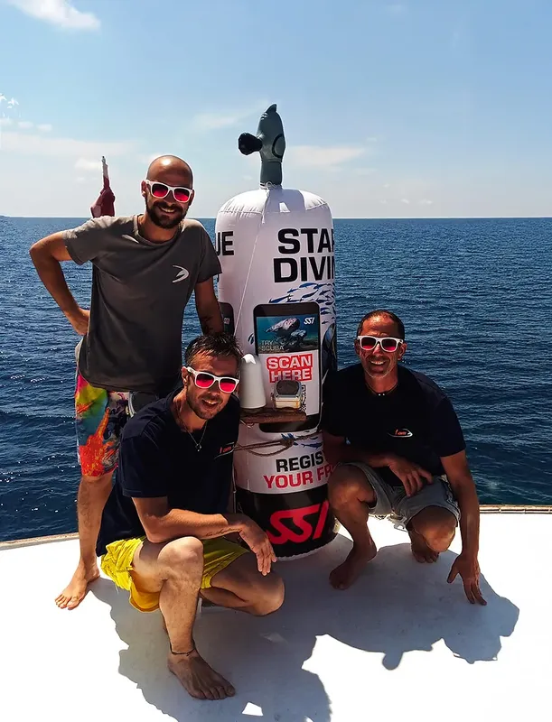 Quatre personnes souriantes sur un bateau avec une bouée publicitaire