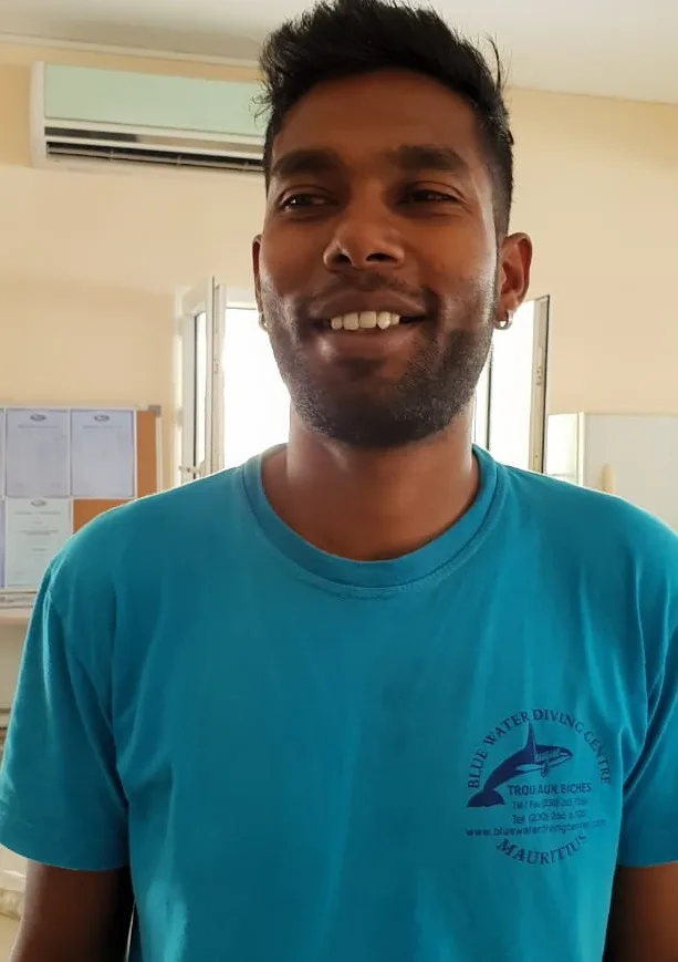 Portrait d'un homme souriant devant un mur clair et une porte