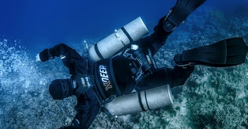 Plongeur en combinaison noire équipé de deux bouteilles sous-marine