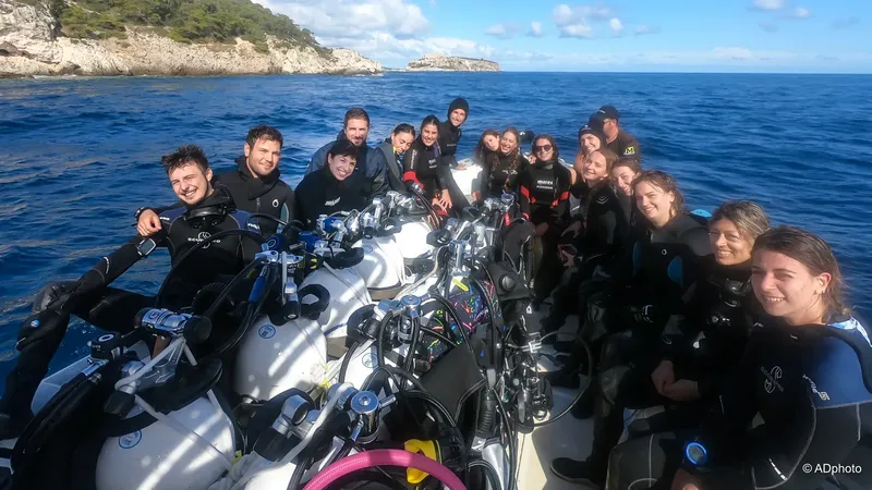 Groupe de plongeurs souriants sur un bateau en mer, équipement visible