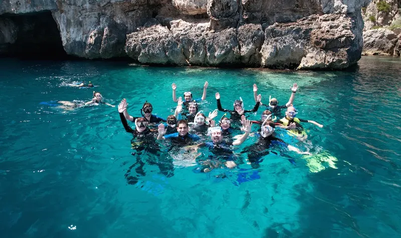 Groupe de plongeurs souriants dans une eau turquoise et claire