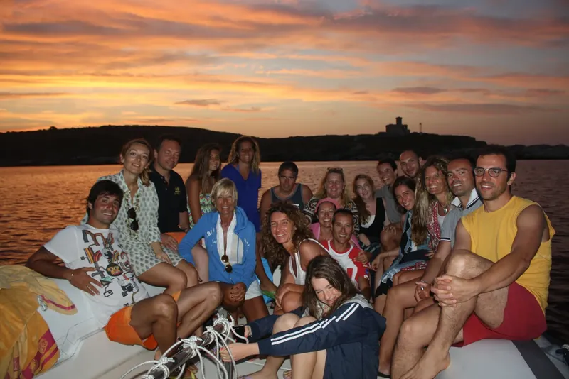 Groupe de personnes souriantes sur un bateau au coucher du soleil