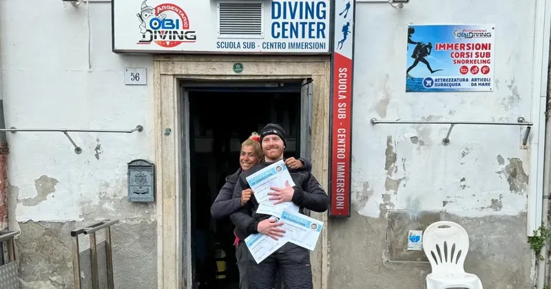 Deux plongeurs souriants présentent leurs certificats devant le centre