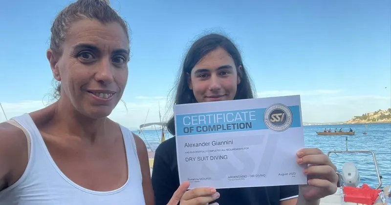 Deux personnes souriantes présentent un certificat de plongée en scaphandre sec