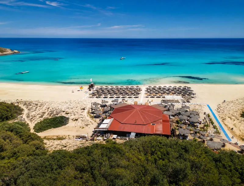 Vue aérienne d'une plage avec un bâtiment et des bateaux en mer