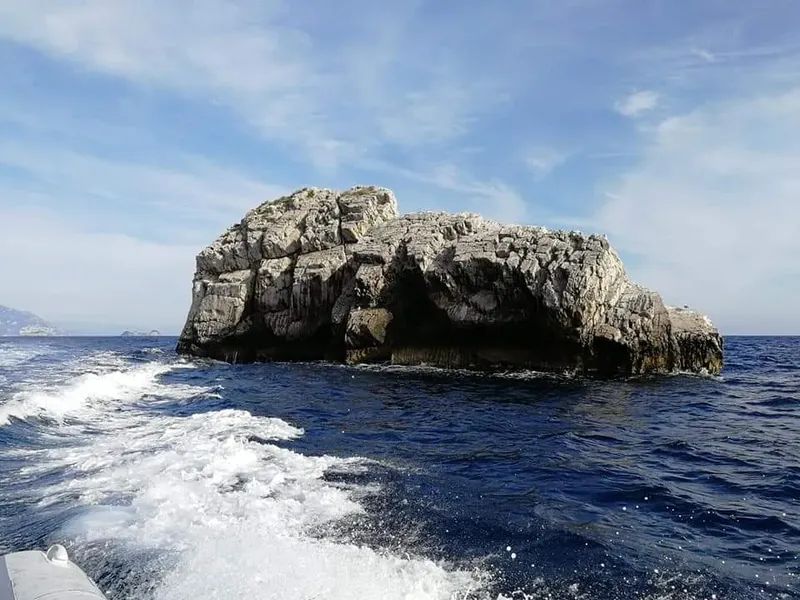 Rocher en mer, vue depuis un bateau, ciel bleu et vagues