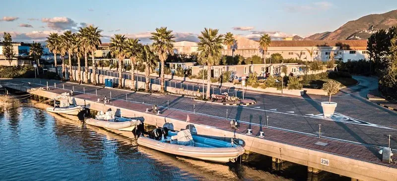 Quai avec bateaux amarrés devant un centre de plongée et palmiers