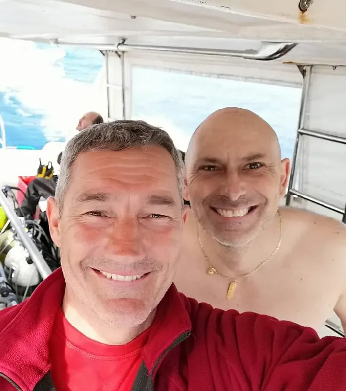 Deux hommes souriants sur un bateau de plongée en mer