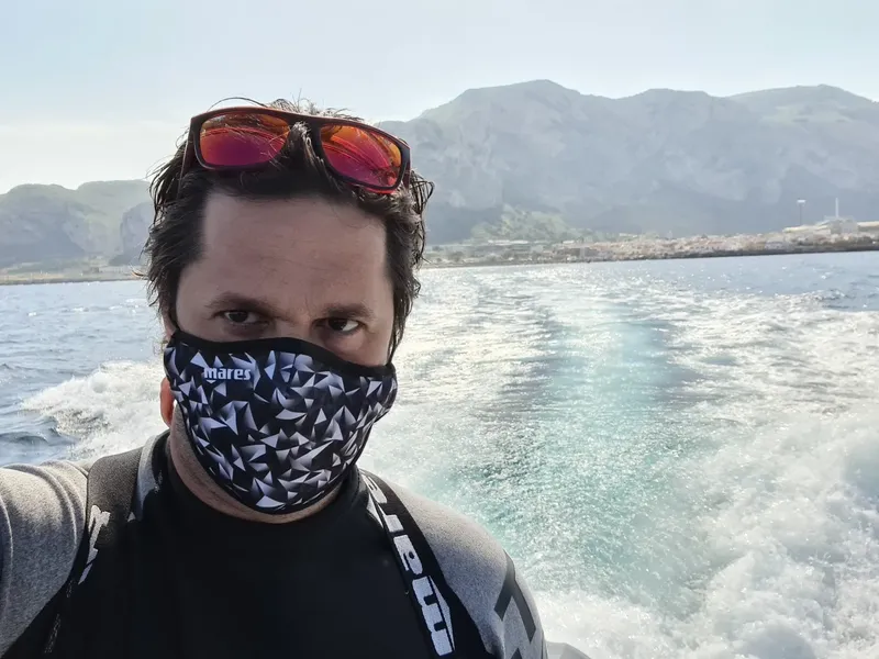 Homme en combinaison de plongée, masque et lunettes sur un bateau