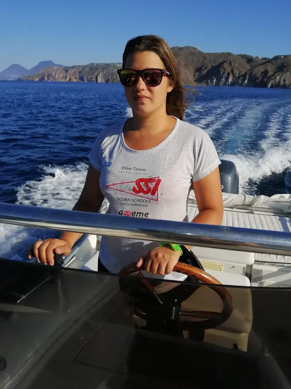 Femme souriante sur un bateau en mer, tenant un volant