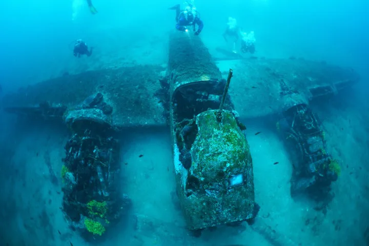 Plongeurs explorant l'épave d'un avion sous-marin bleu clair