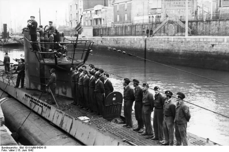 Groupe d'hommes alignés sur un sous-marin amarré dans un port