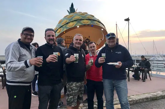 Groupe de personnes souriantes avec des verres sur un quai ensoleillé