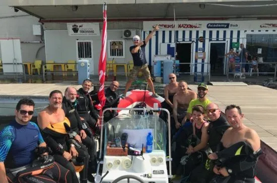 Groupe de plongeurs souriants posent devant le centre et le bateau