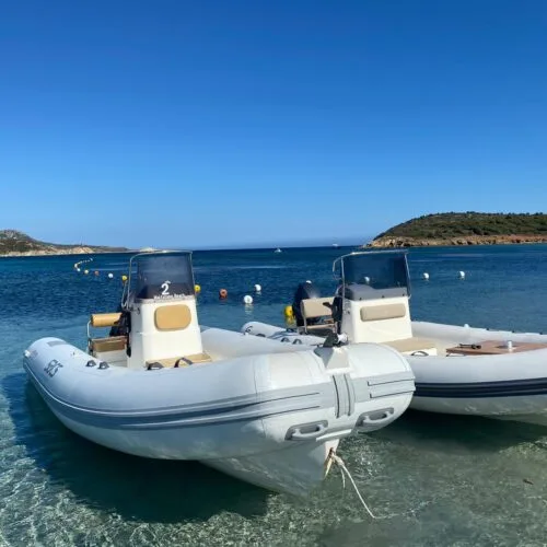 Deux bateaux semi-rigides amarrés dans une eau turquoise sous un ciel bleu