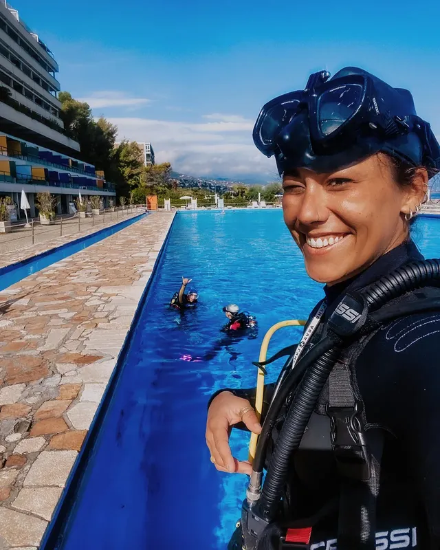 Plongeuse souriante en équipement complet dans une piscine ensoleillée