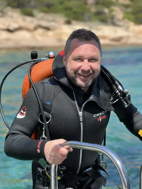 Plongeur souriant en combinaison, prêt à explorer les fonds marins