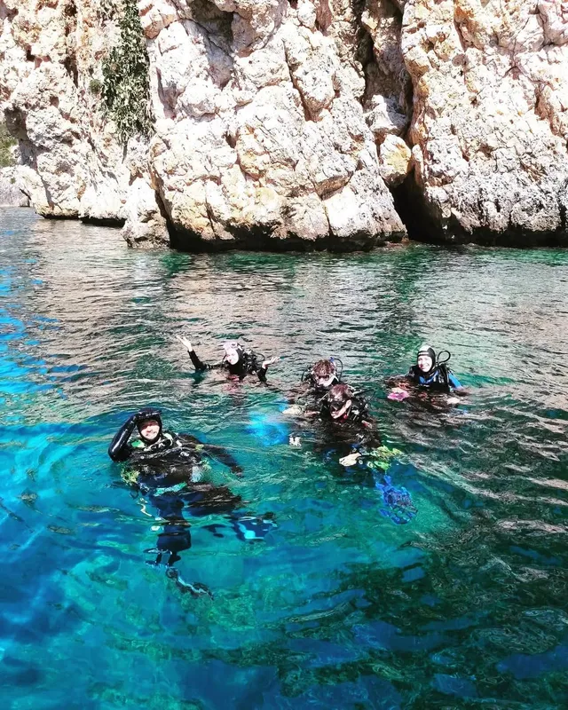 Plongeurs en surface dans une eau turquoise, falaise rocheuse en arrière-plan