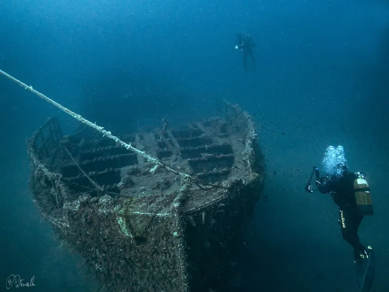Deux plongeurs explorent l'épave d'un bateau en mer profonde