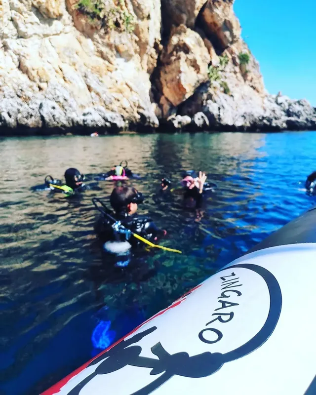 Plongeurs explorent les fonds marins depuis un bateau, eau turquoise et rocheuses
