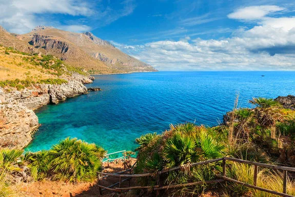 Côte rocheuse avec mer bleue et ciel nuageux ensoleillé