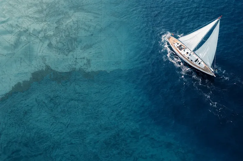 Voilier blanc naviguant sur une mer bleue claire vue d'en haut
