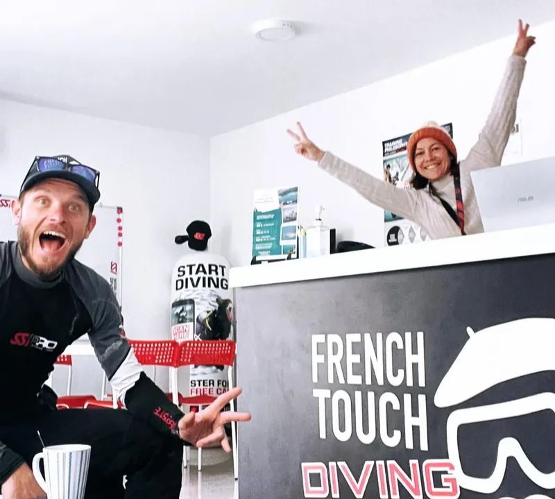 Deux personnes souriantes et enthousiastes au comptoir d'un centre de plongée