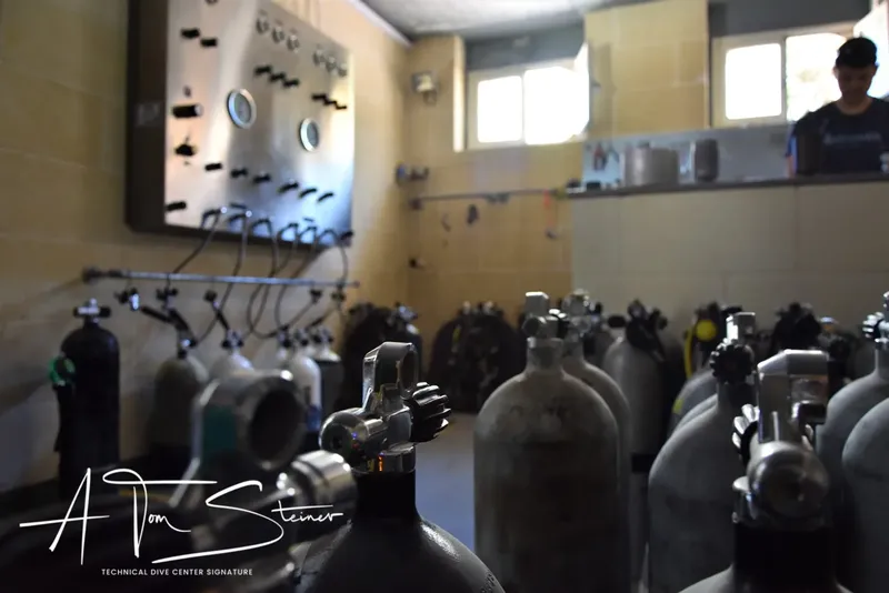 Rangées de bouteilles de plongée et personne dans un local du centre