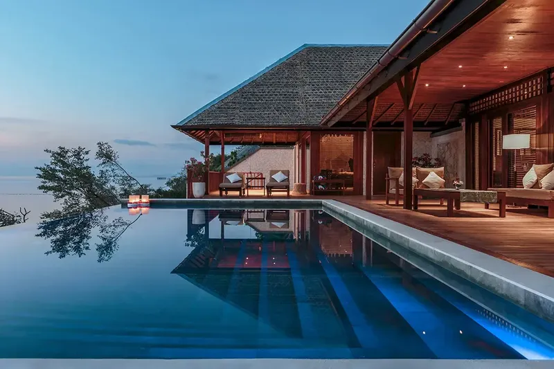 Piscine à débordement avec vue sur la mer et bâtiment éclairé