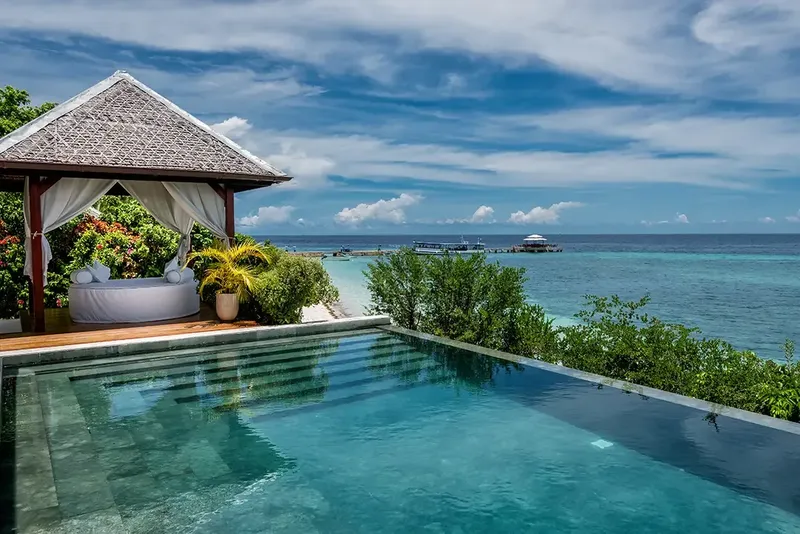 Vue sur mer turquoise avec piscine à débordement et gazebo relaxant