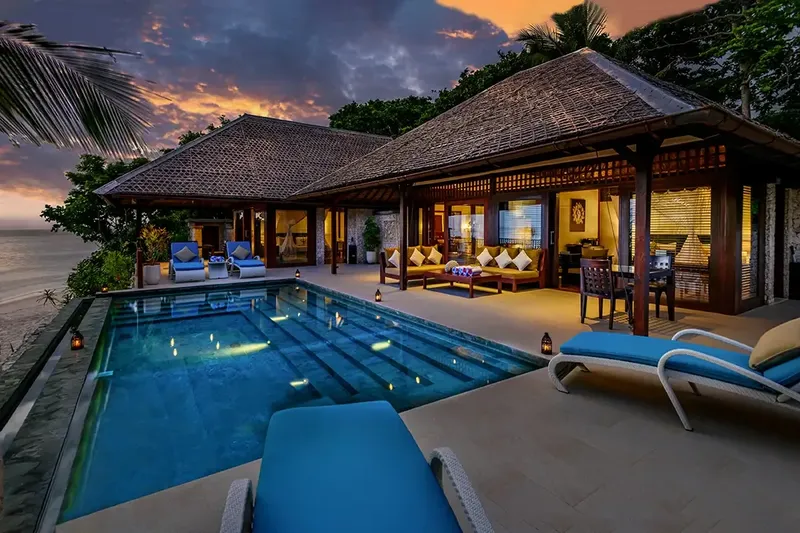 Bâtiment avec piscine, transats et vue sur la mer au coucher du soleil