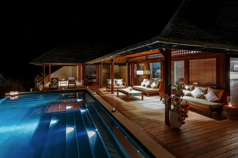 Piscine éclairée et terrasse en bois avec mobilier de détente nocturne