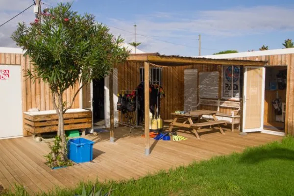 Terrasse en bois avec matériel de plongée, abri et végétation luxuriante