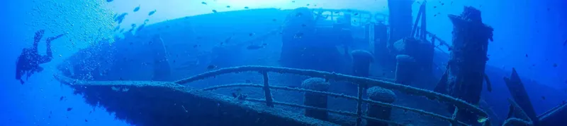 Plongeur explorant l'épave d'un navire sous l'eau bleu profond