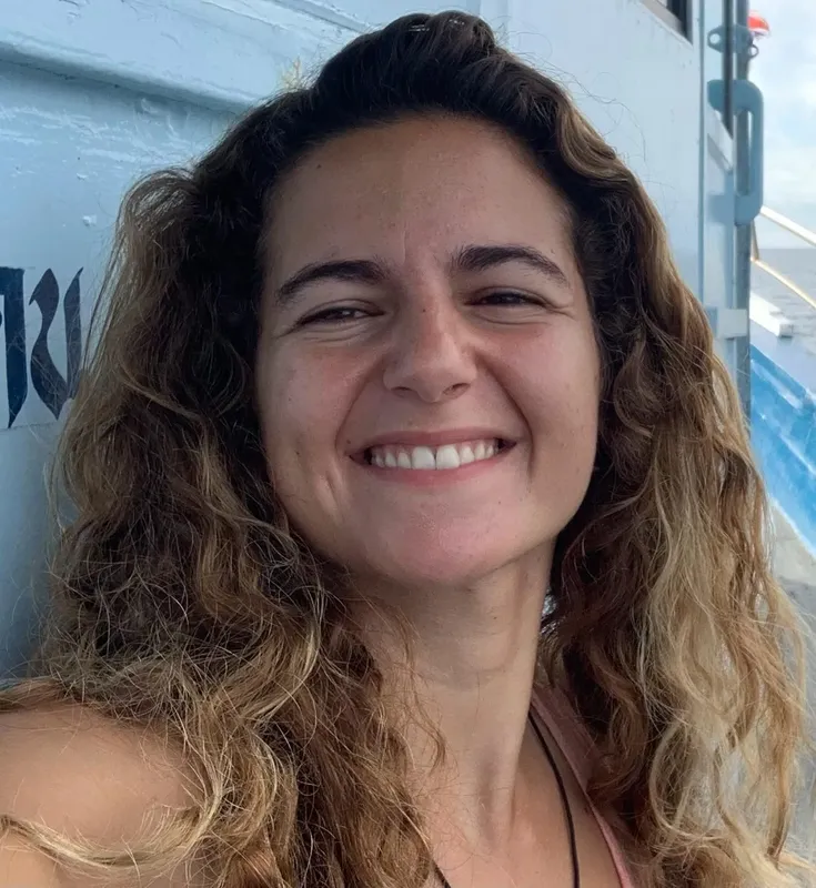 Portrait souriant d'une femme aux cheveux bruns et ondulés en extérieur