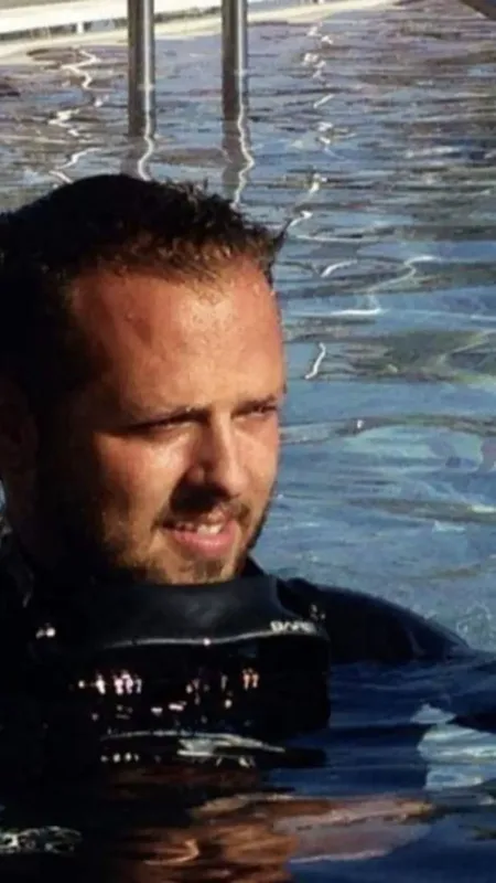 Homme en combinaison de plongée, regardant vers la droite, dans l'eau