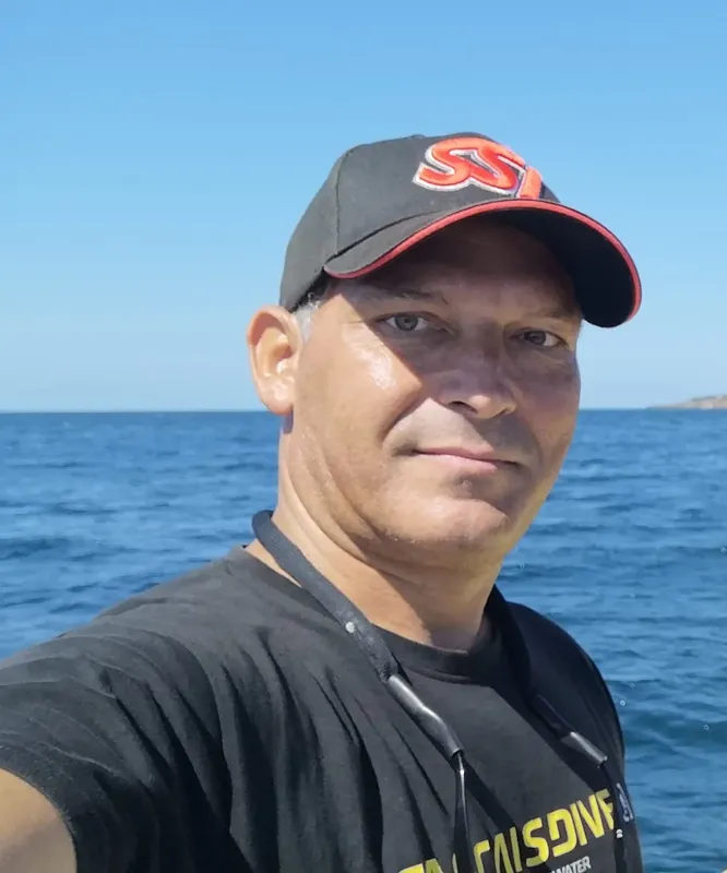Homme souriant portant une casquette et un t-shirt sur un bateau