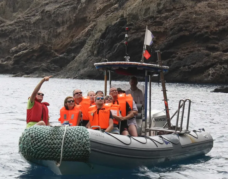 Groupe de personnes à bord d'un semi-rigide en mer, pointant vers l'avant