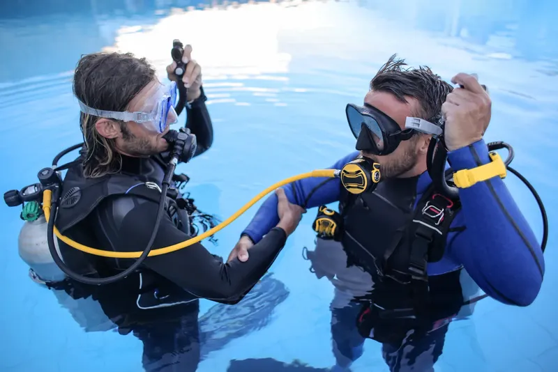 Deux plongeurs s'entraînent en piscine, vérification du matériel et communication
