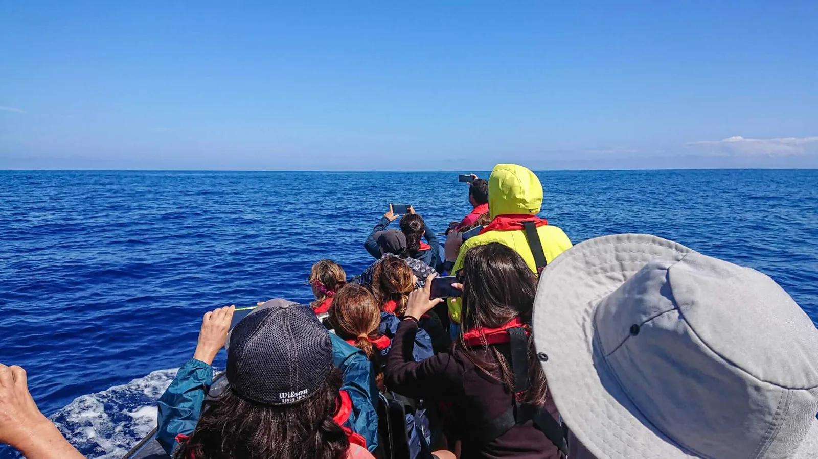 Groupe de personnes à bord d'un bateau en mer, regardant au loin
