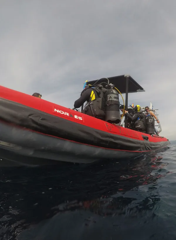 Plongeurs équipés sur un bateau semi-rigide rouge en mer