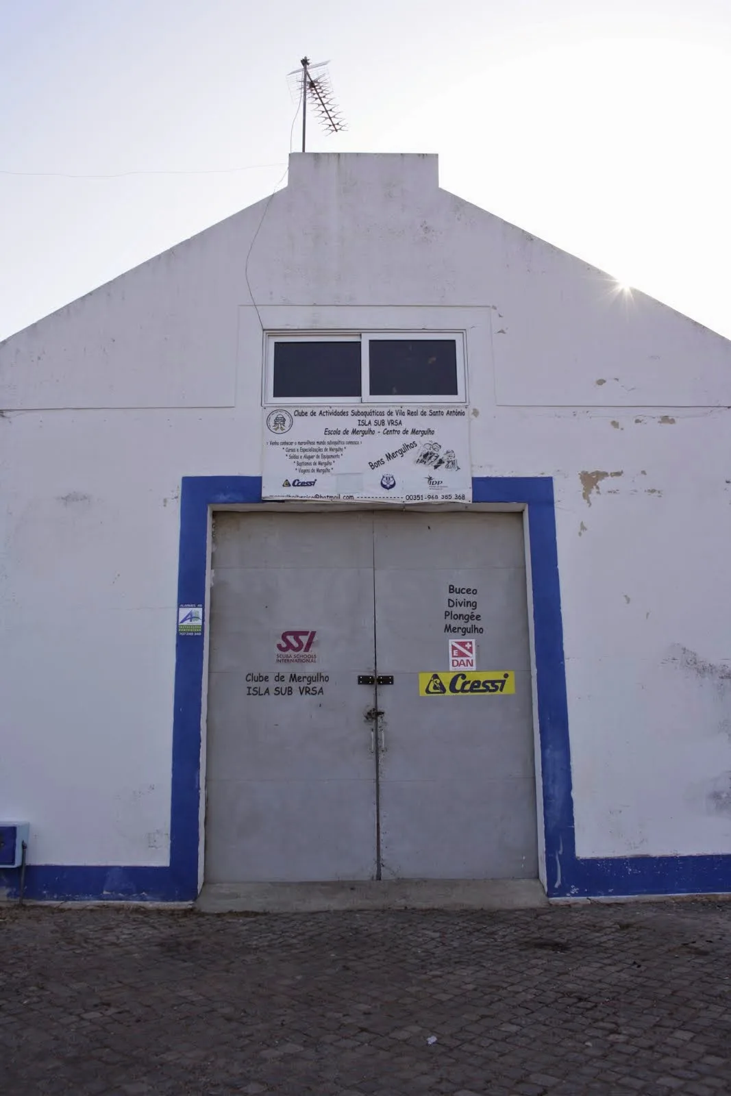 Façade d'un bâtiment blanc avec une porte et des logos de plongée