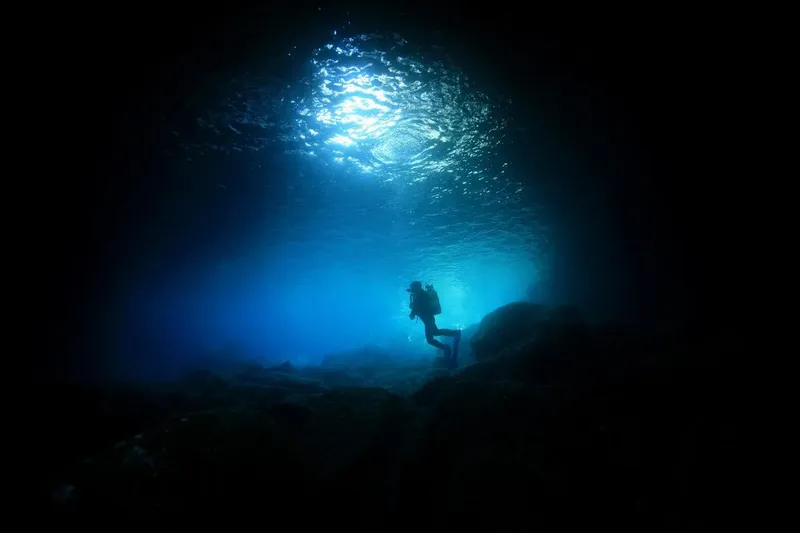 Plongeur silhouette sombre explorant un récif sous la lumière du soleil