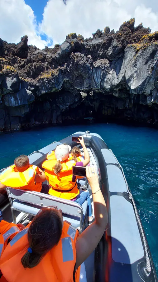 Personnes en gilet de sauvetage sur un bateau en mer face à des falaises