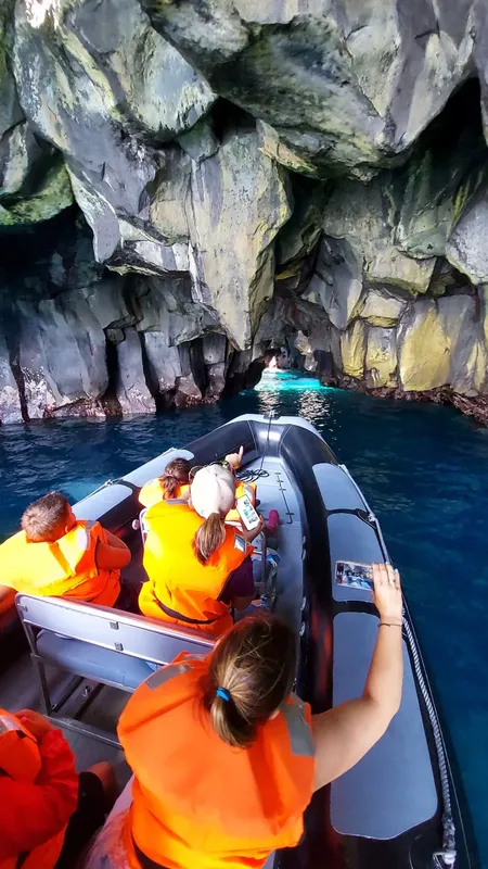 Personnes en gilet de sauvetage dans un bateau explorant une grotte marine